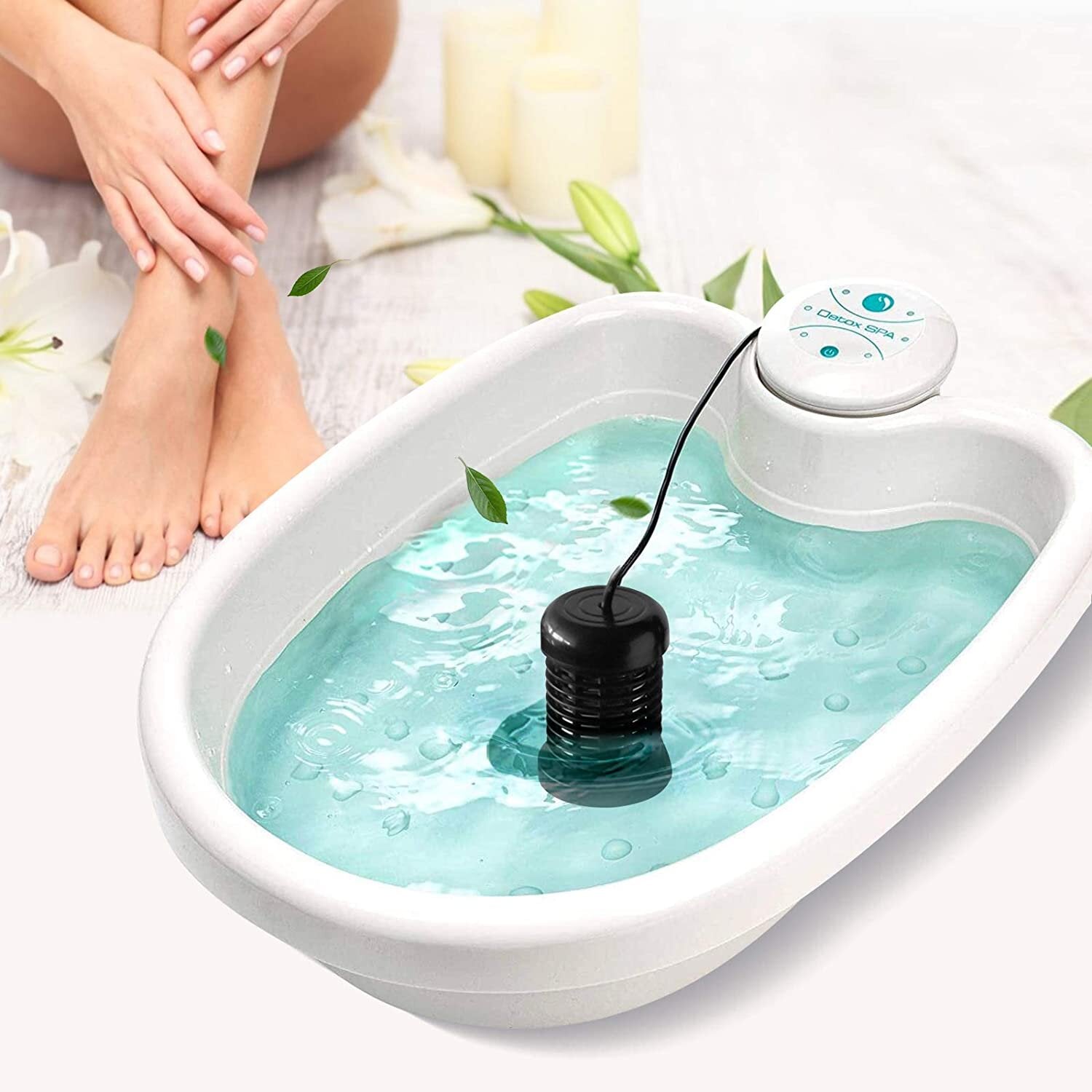 Foot bath with water and a black pump, surrounded by white flowers and a candle.